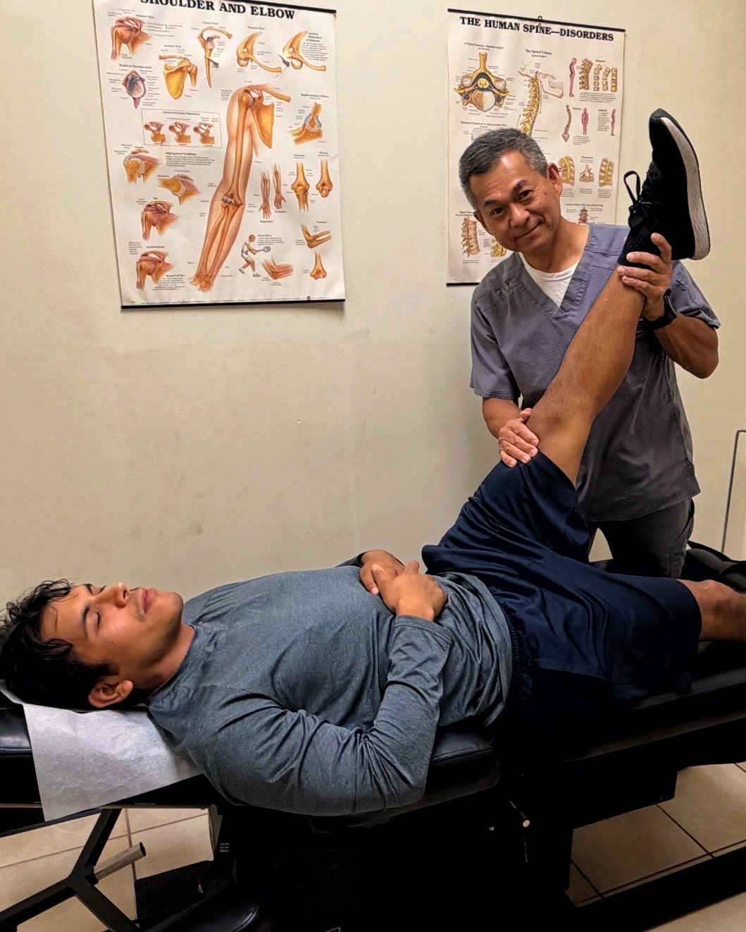 Dr. Bui performing a straight-leg raise assessment on a patient lying on a treatment table